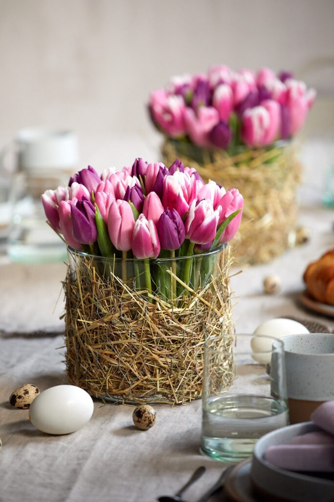Pinke Tulpen in einer Vase mit ummantelter Heudekoration
